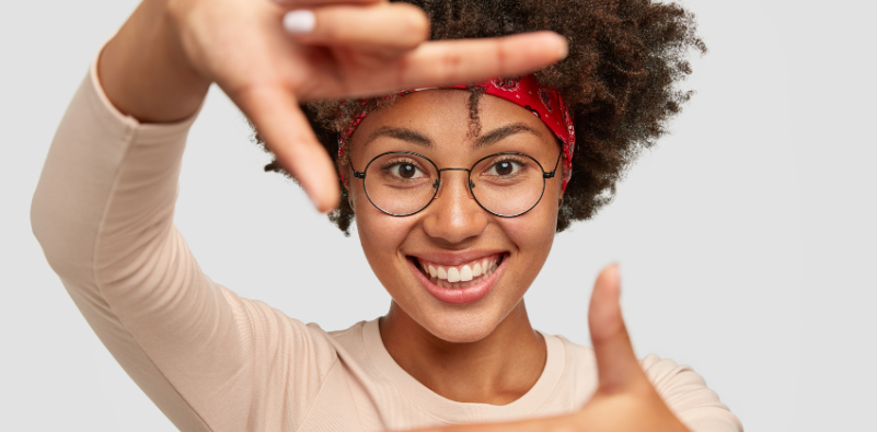 Cheerful woman making a frame with both hands while smiling