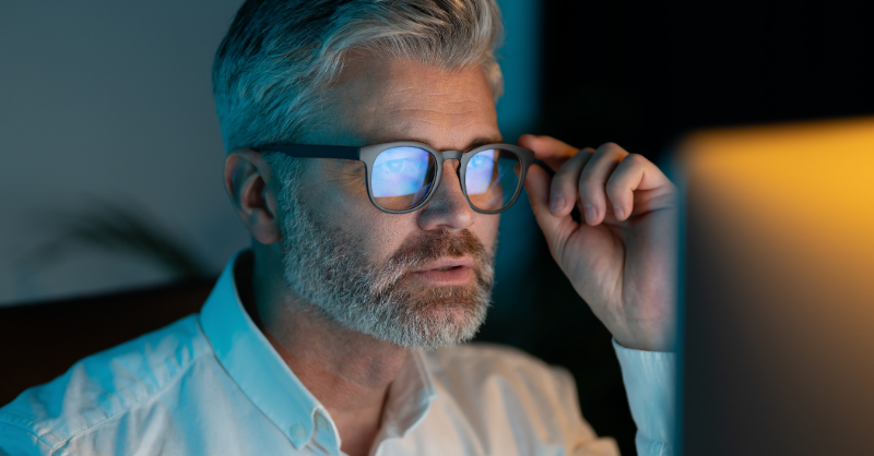 A man wearing blue light lenses looking at his laptop