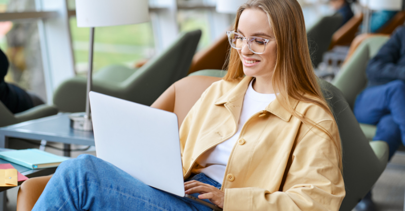 A college student wearing glasses studying on her laptop.