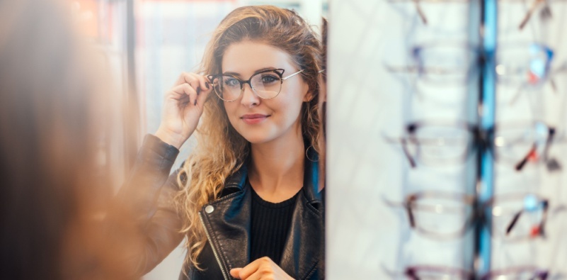 A young woman trying on eyeglasses at the eye doctor’s office.