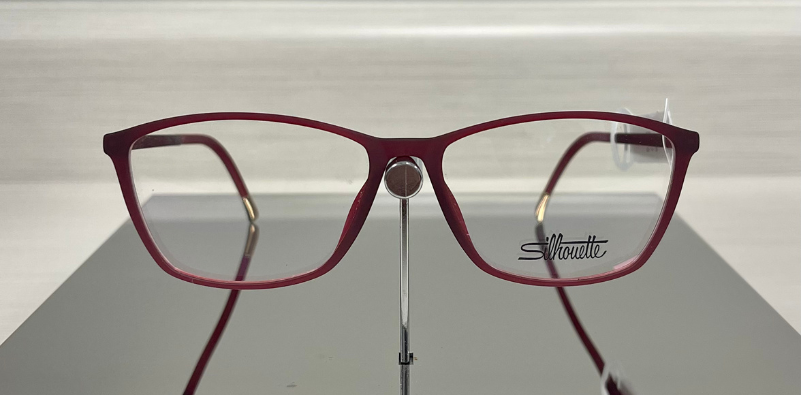 A pair of red Silhouette eyeglasses on a stand at the eye doctor’s office.